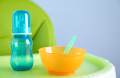 Photo of Set of plastic dishware on white feeding table. Serving baby food