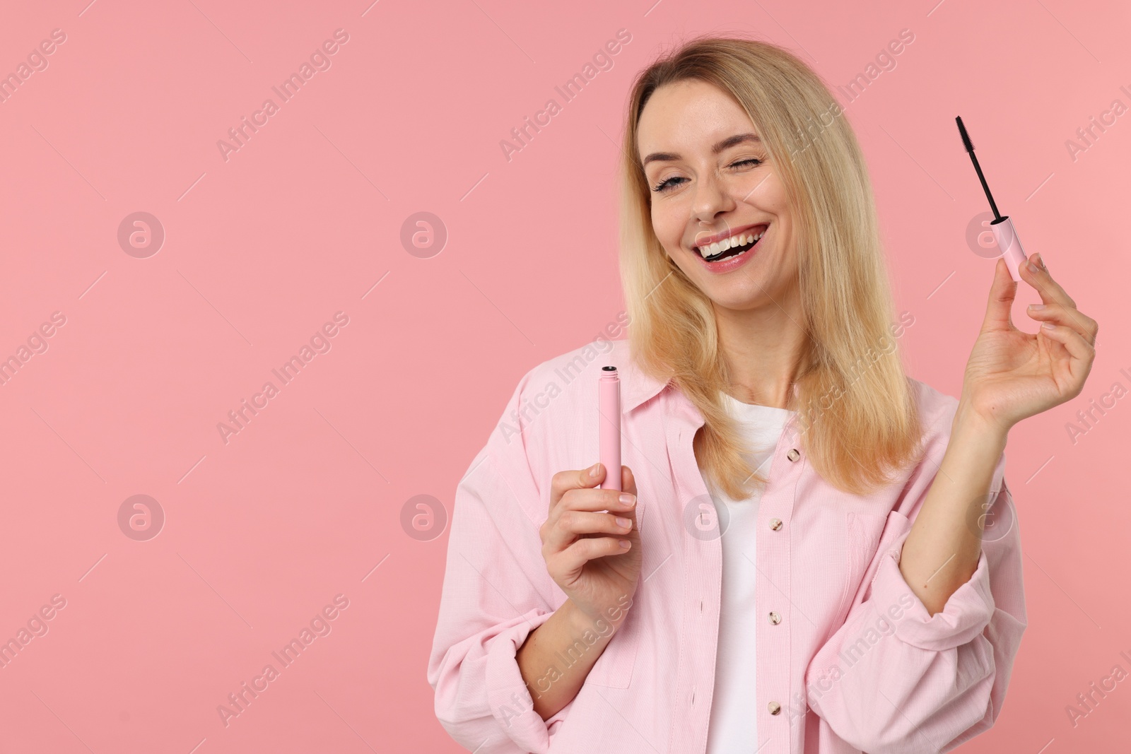 Photo of Beautiful woman with mascara on pink background, space for text