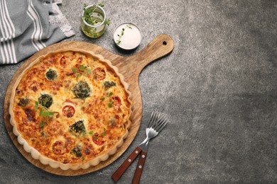 Photo of Delicious homemade vegetable quiche, oregano, salt and oil on gray table, flat lay. Space for text