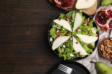 Photo of Delicious pear salad in bowl served on wooden table, flat lay. Space for text