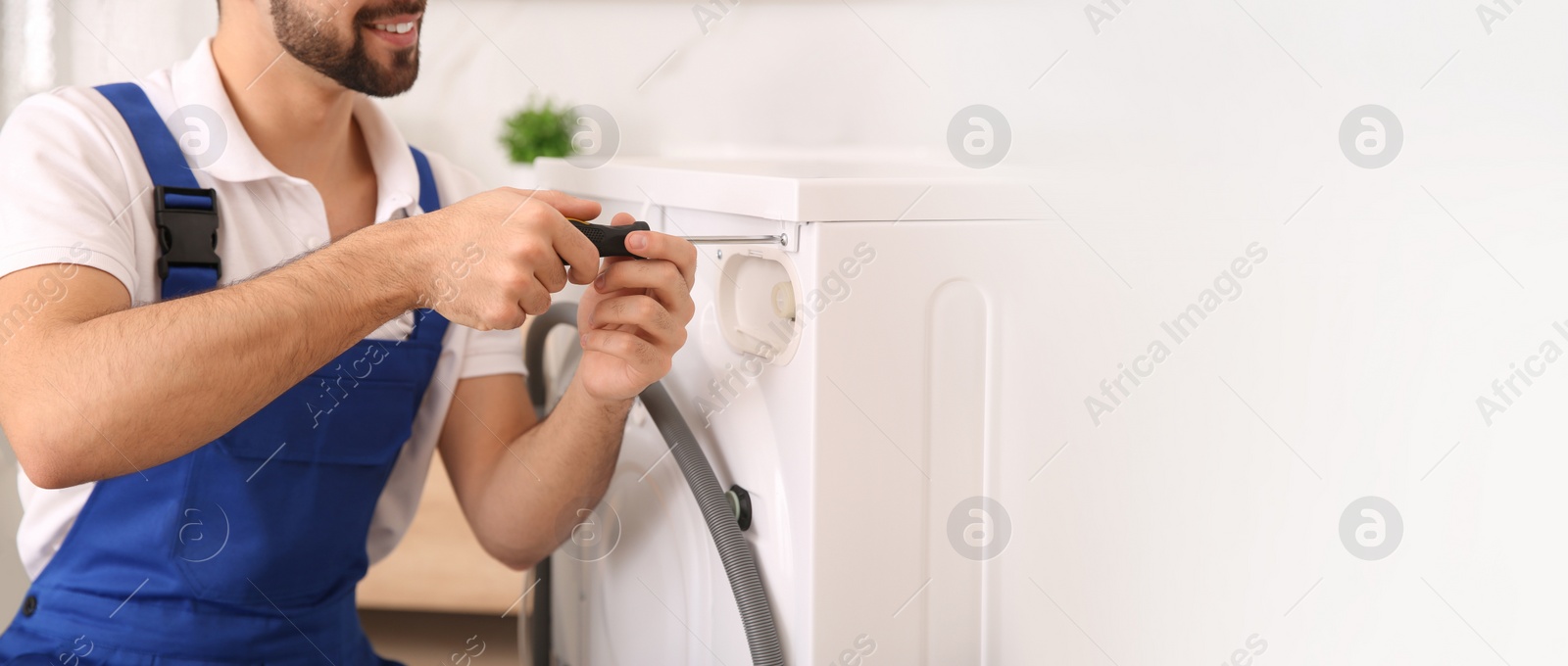 Image of Professional plumber repairing washing machine in bathroom, space for text. Banner design