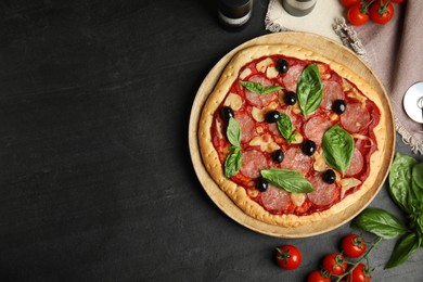 Photo of Delicious homemade pita pizza and ingredients on black table, flat lay. Space for text