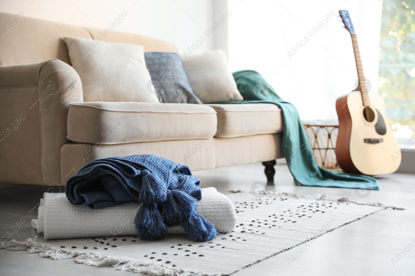 Photo of Folded plaids near comfortable sofa in stylish living room interior