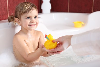 Photo of Mother playing with her little daughter in bathroom, closeup