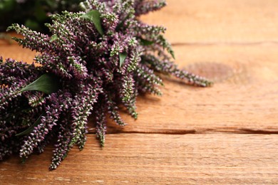 Photo of Beautiful autumnal wreath with heather flowers on wooden background, closeup. Space for text