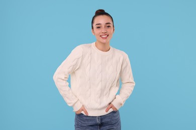 Photo of Beautiful young woman in stylish warm sweater on light blue background