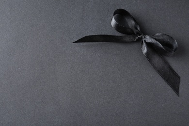 Photo of Black ribbon bow on dark background, above view with space for text. Funeral symbol