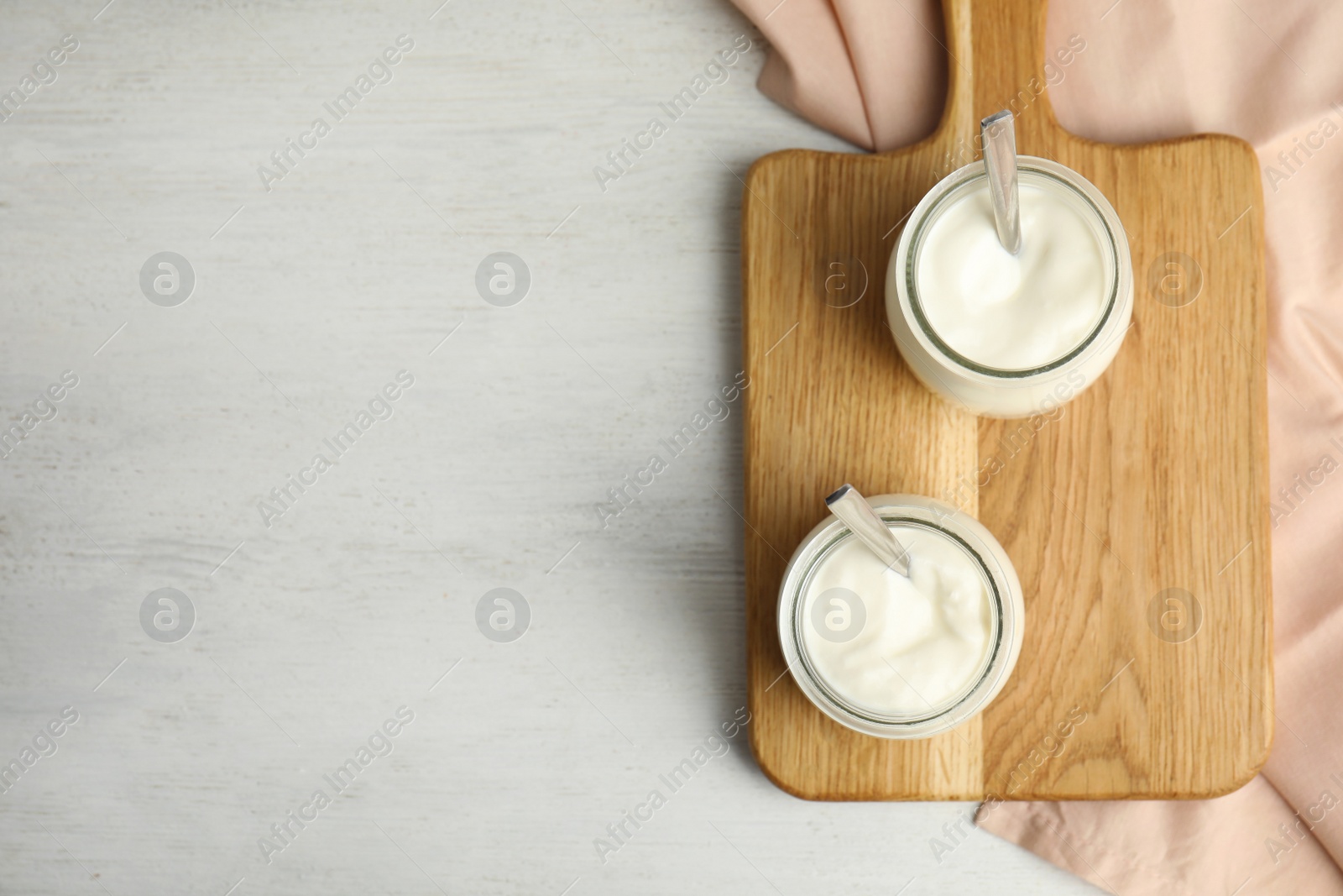 Photo of Tasty organic yogurt on white wooden table, flat lay. Space for text