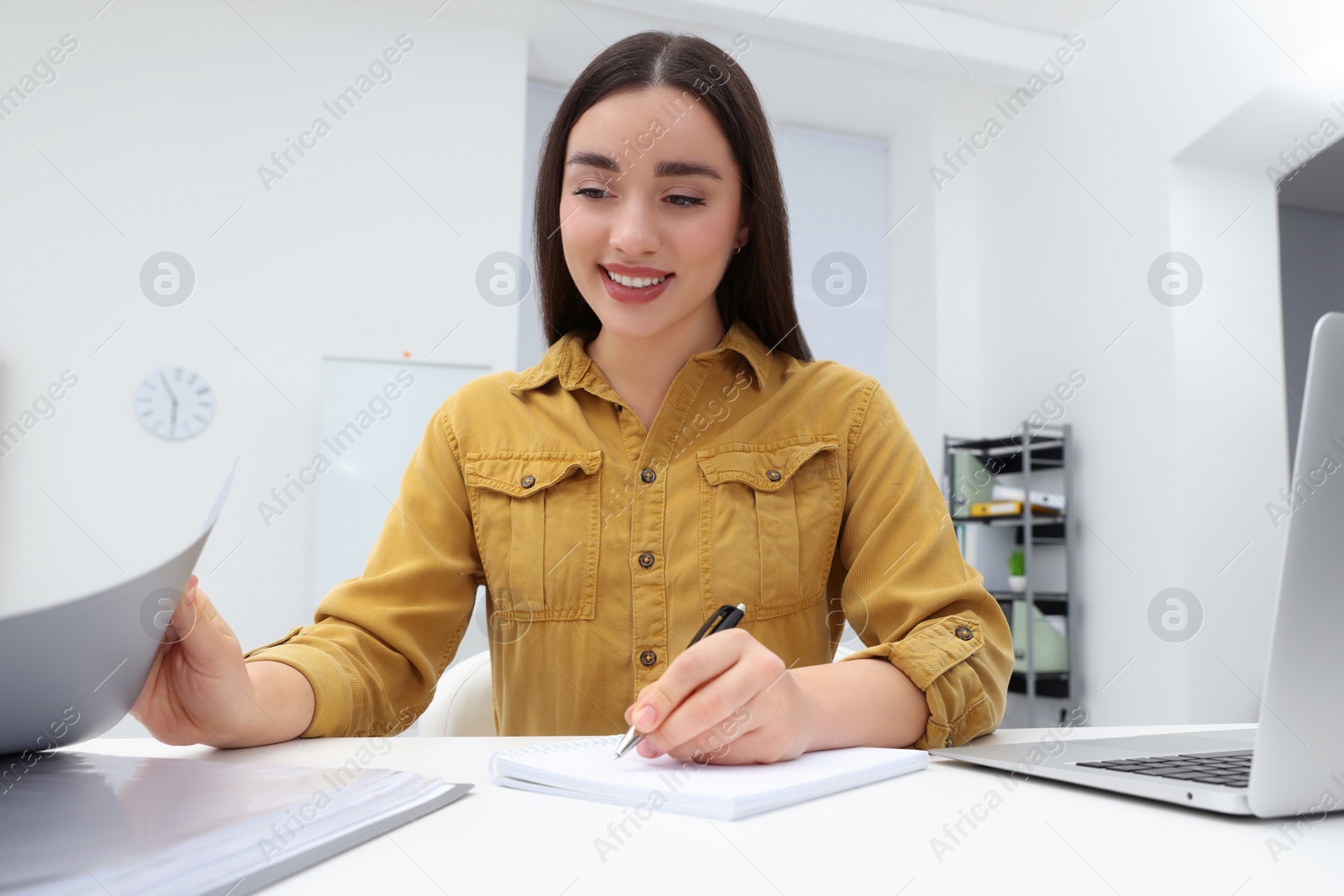 Photo of Young female intern working at table in office