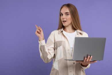 Special promotion. Young woman with laptop pointing at something on violet background, space for text