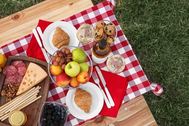 Photo of Picnic table with different tasty snacks, top view