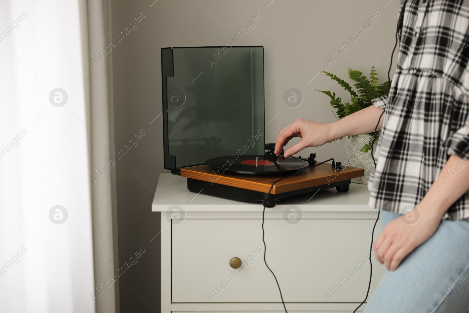 Photo of Young woman using turntable at home, closeup