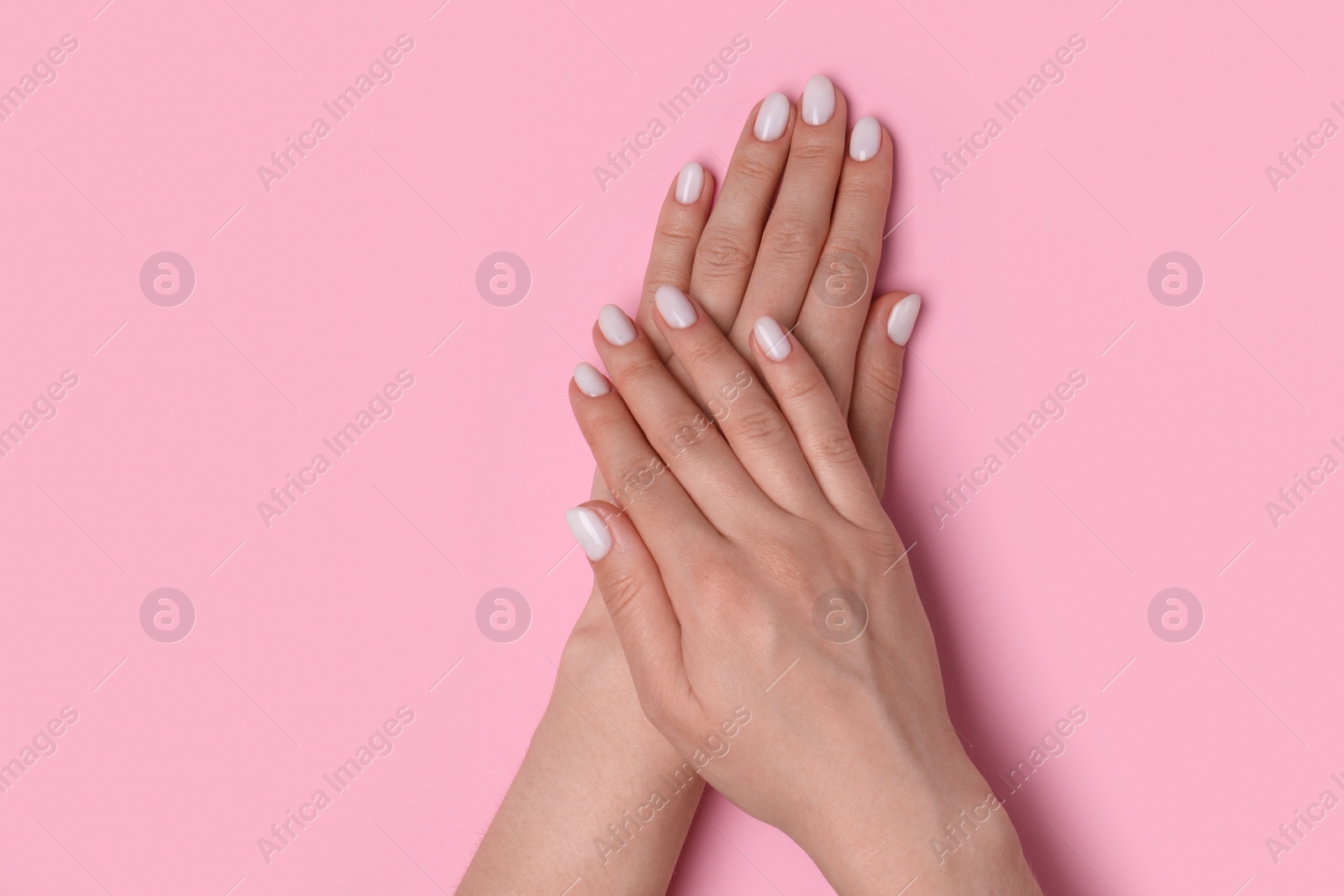 Photo of Woman showing her manicured hands with white nail polish on pink background, top view. Space for text