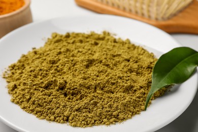 Photo of Henna powder and green leaf on white table, closeup. Natural hair coloring