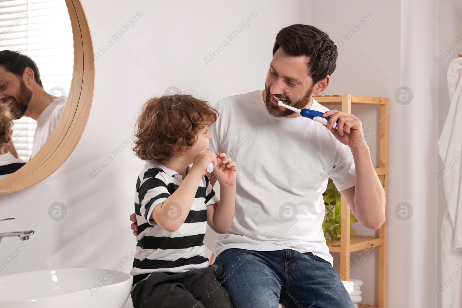 Photo of Father and his son brushing teeth together in bathroom