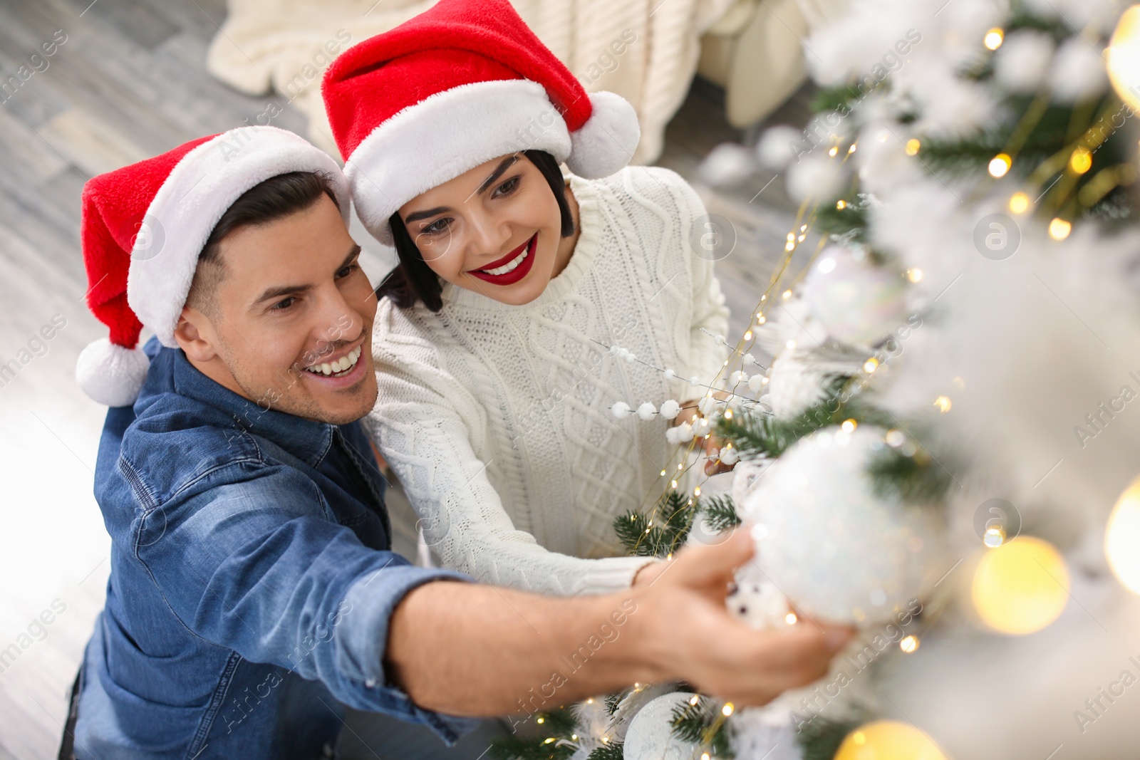 Photo of Happy couple decorating Christmas tree at home, above view