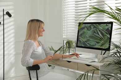Photo of Woman working on computer at table in room. Interior design