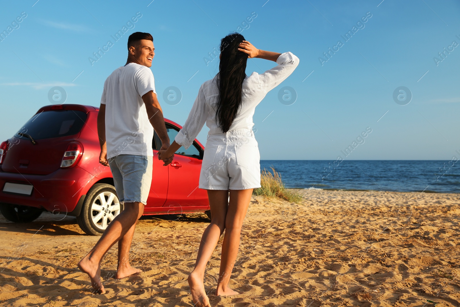 Photo of Happy couple walking on sandy beach. Summer trip