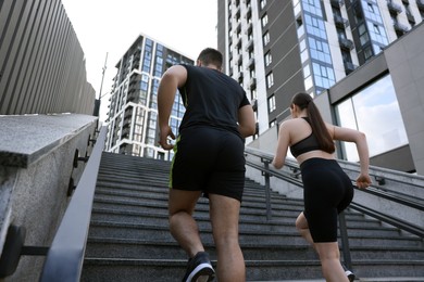 Photo of Healthy lifestyle. Couple running up steps outdoors, low angle view