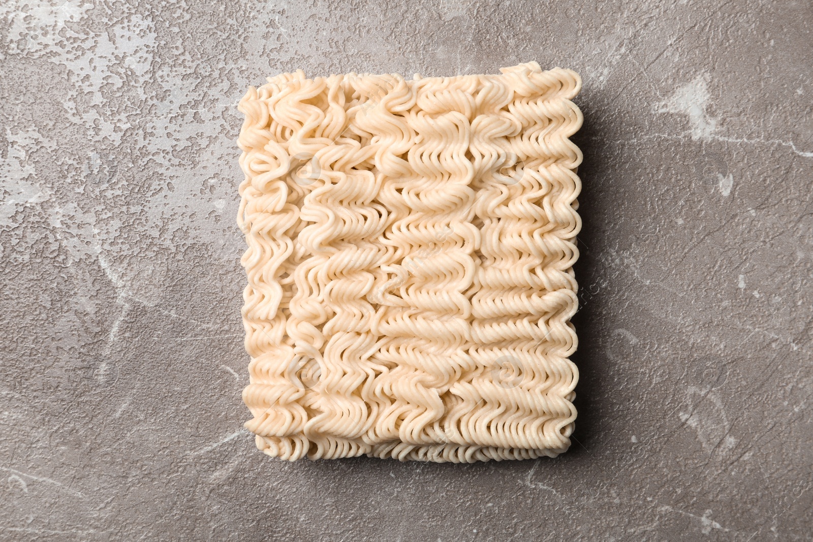 Photo of Block of quick cooking noodles on color background, top view