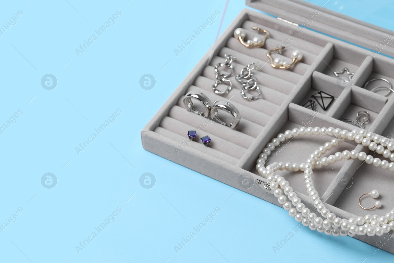 Photo of Jewelry box with many different accessories on light blue background, space for text