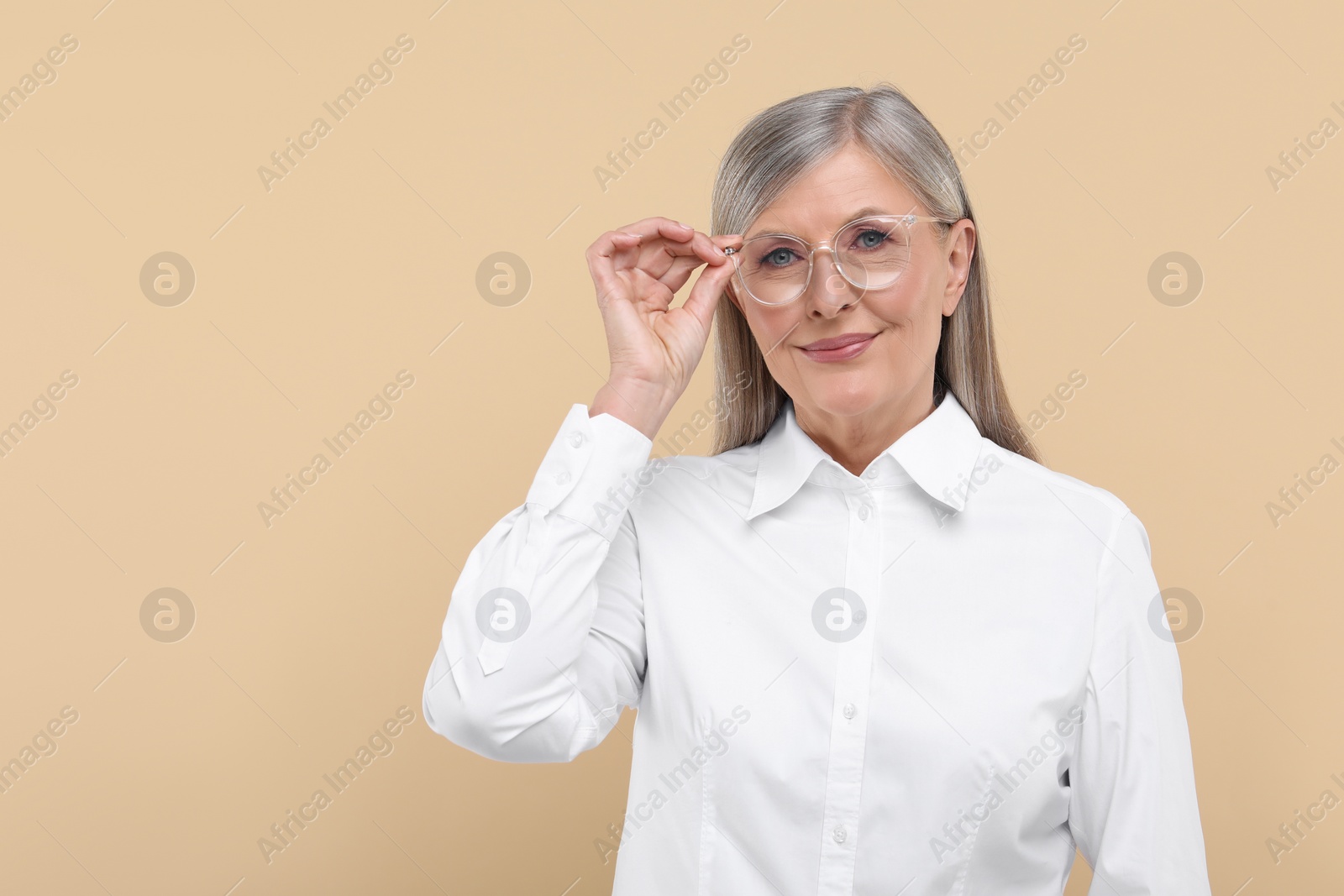 Photo of Portrait of beautiful senior woman in glasses on beige background. Space for text