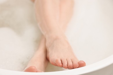 Photo of Woman taking bath with foam in tub, closeup