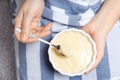 Photo of Woman holding bowl with vanilla pudding, closeup