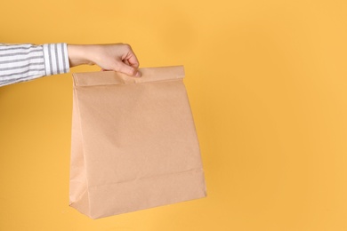 Woman holding paper bag on color background. Mockup for design