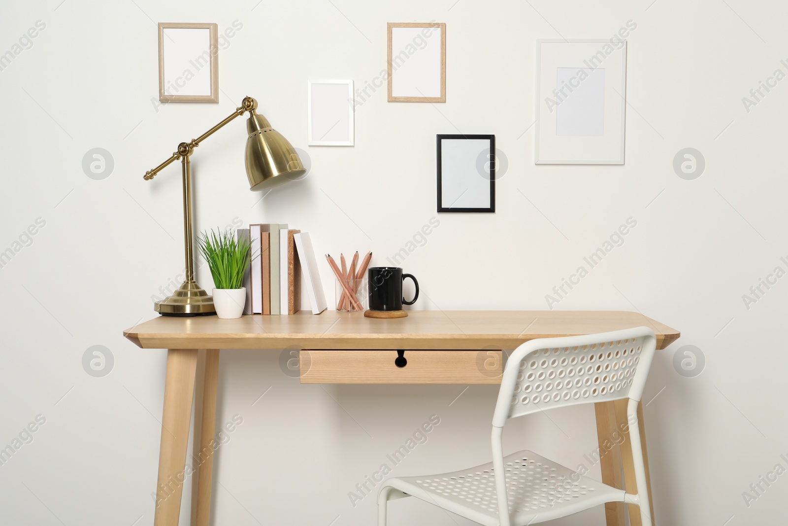 Photo of Comfortable workplace with wooden desk near white wall