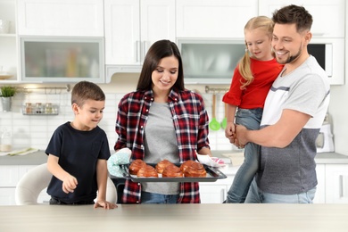 Photo of Happy family with tray of oven baked buns in kitchen