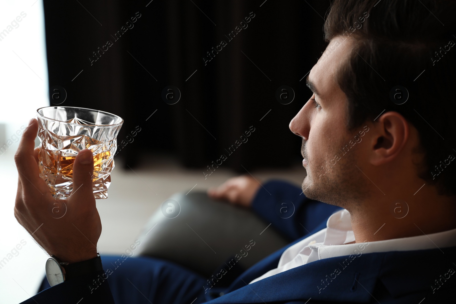 Photo of Young man with glass of whiskey indoors