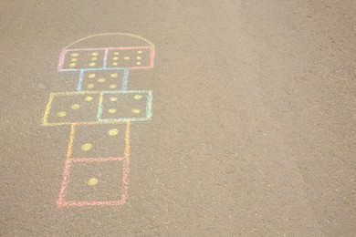 Photo of Hopscotch drawn with colorful chalk on asphalt outdoors. Space for text