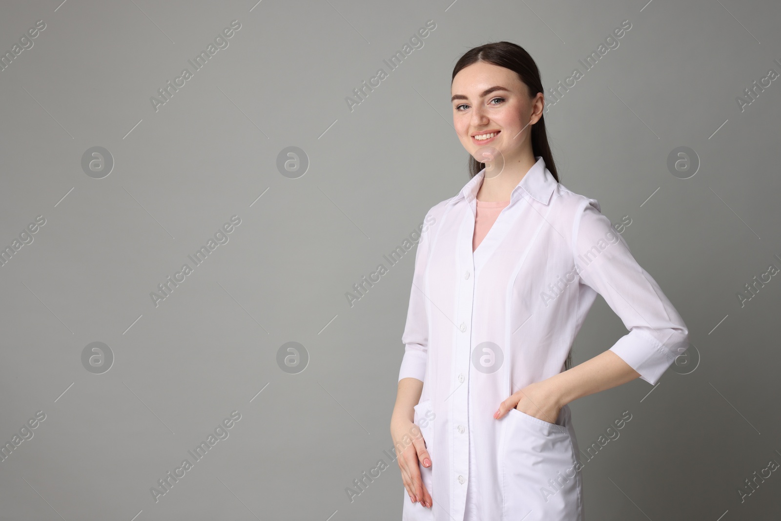 Photo of Cosmetologist in medical uniform on grey background, space for text