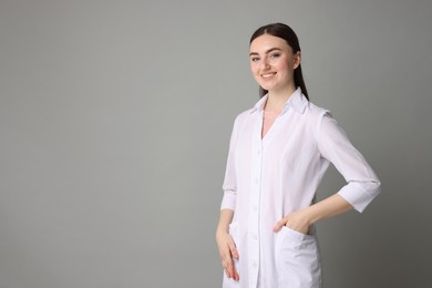 Cosmetologist in medical uniform on grey background, space for text