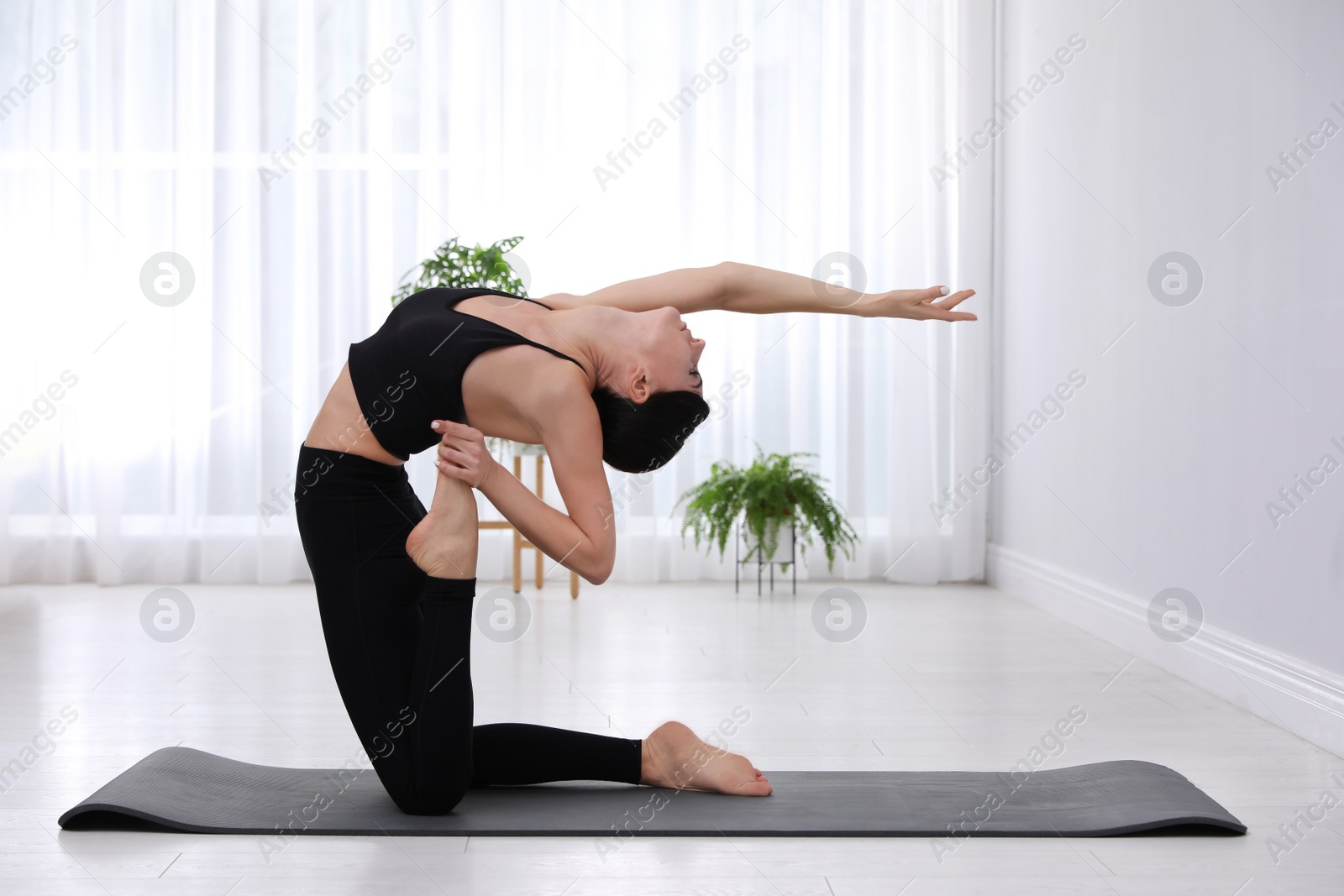 Photo of Professional young acrobat practicing yoga at home