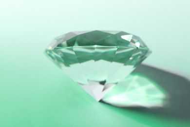 Photo of Beautiful dazzling diamond on light green background, closeup