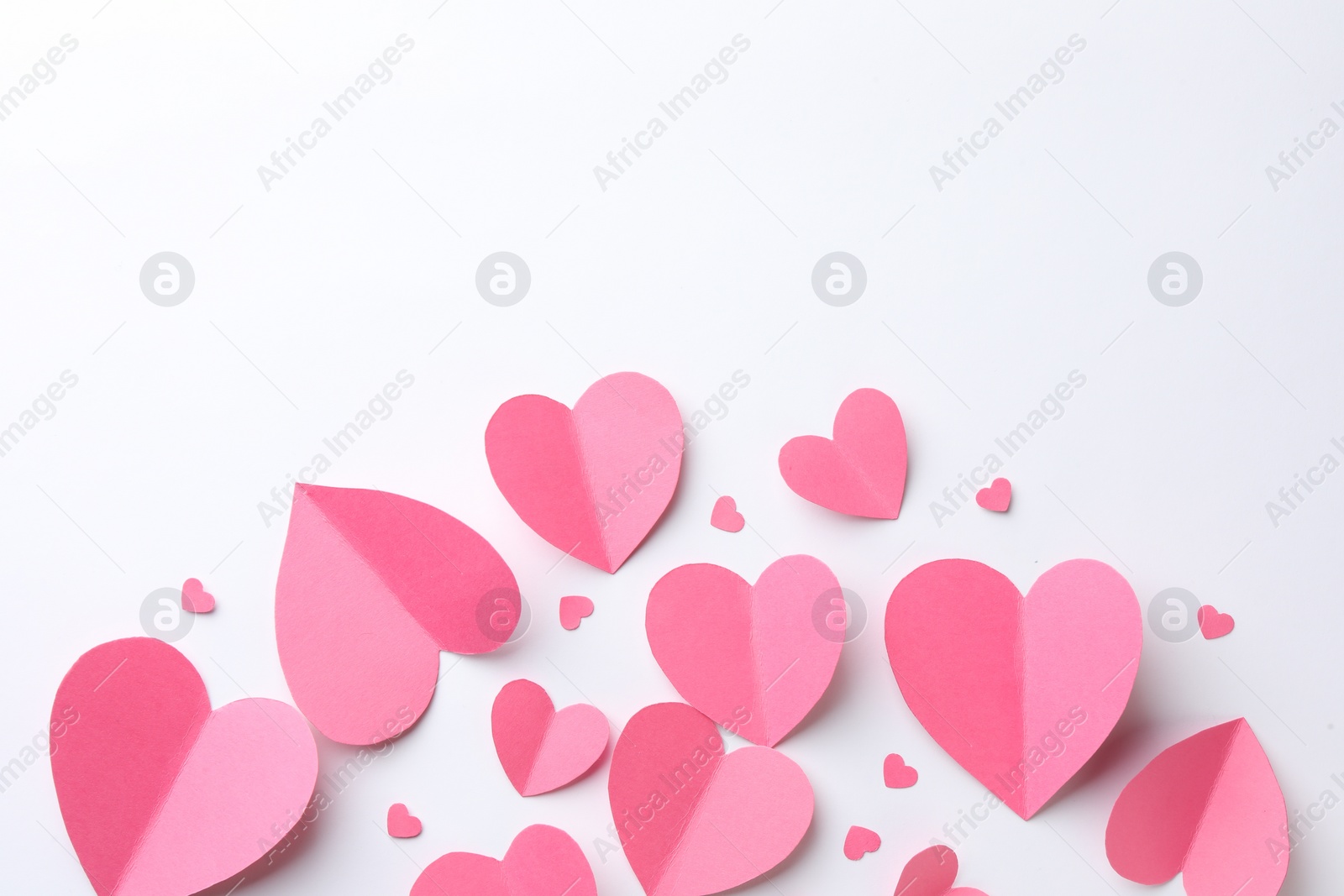 Photo of Pink paper hearts on white background, flat lay. Space for text