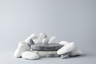 Photo of Presentation for product. Stone podium and pebbles on light grey background. Space for text