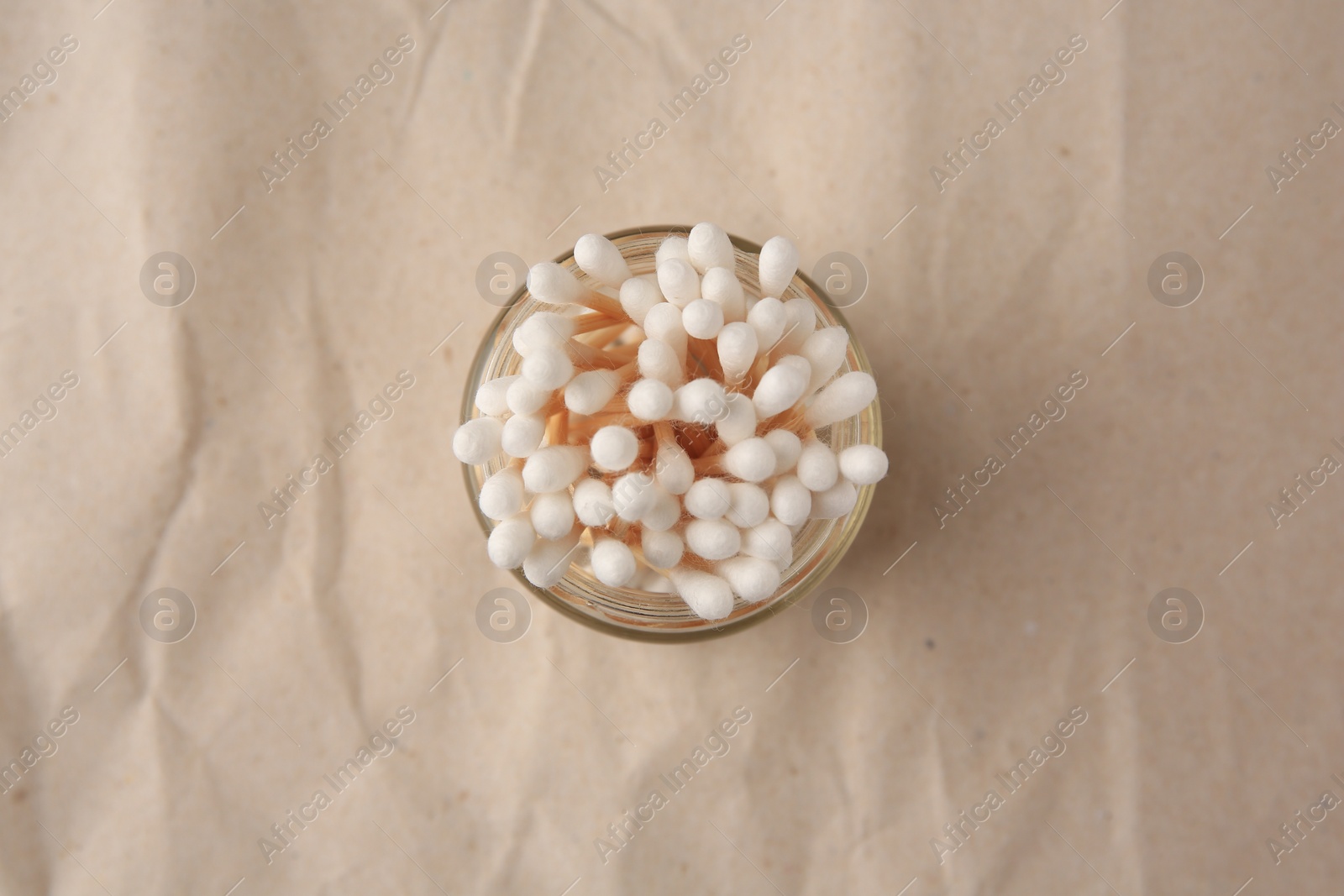 Photo of Jar of clean cotton buds on crumpled paper, top view