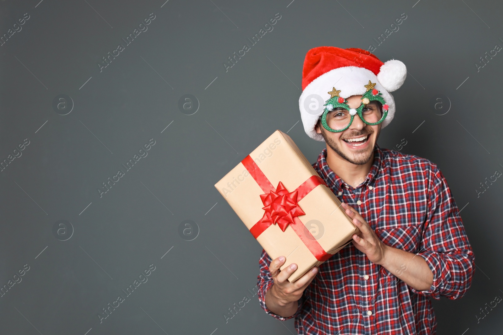 Photo of Young man with Christmas gift on grey background