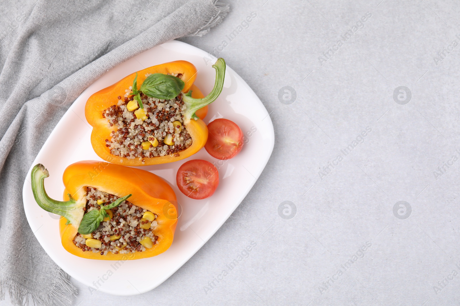 Photo of Quinoa stuffed bell pepper with basil and tomato on light table, top view. Space for text