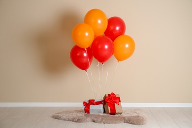 Photo of Bunch of bright balloons and gifts on floor against color wall