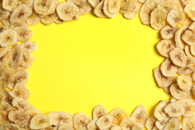 Photo of Frame made of sweet banana slices on color background, top view with space for text. Dried fruit as healthy snack