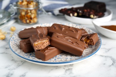 Photo of Delicious chocolate candy bars on white marble table, closeup