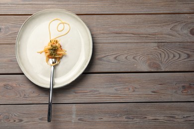 Photo of Heart made with spaghetti and fork on wooden table, top view. Space for text