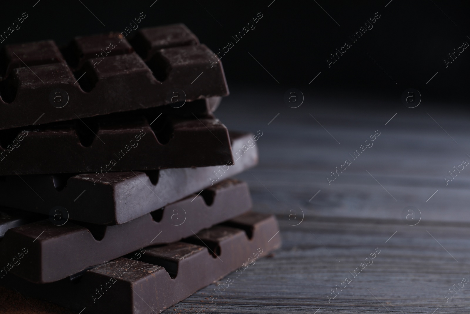 Photo of Tasty dark chocolate bars on wooden table. Space for text