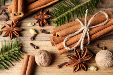 Photo of Different aromatic spices and fir branches on wooden table, closeup