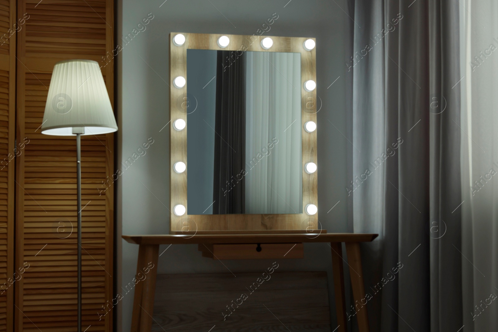 Photo of Beautiful mirror with light bulbs and lamp in makeup room