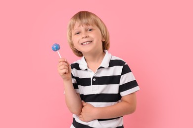 Photo of Happy little boy with lollipop on pink background